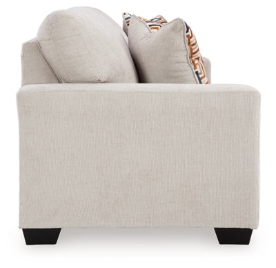 Ashley Furniture Aviemore sofa with plush fabric, cushioned arms, and wooden legs, shown from the side in a modern living room setting.