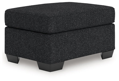 Ashley Furniture Jasmine Peaks Ottoman featuring a plush fabric cover and wooden legs, shown from an angled view.