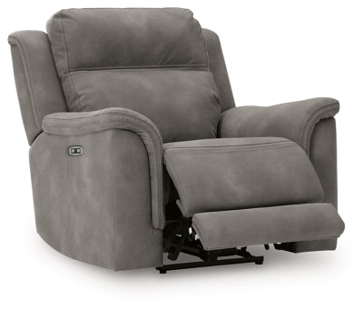 Ashley Furniture Next-Gen DuraPella Power Recliner shown from an angle with the seat open, featuring plush cushioning and a modern design.