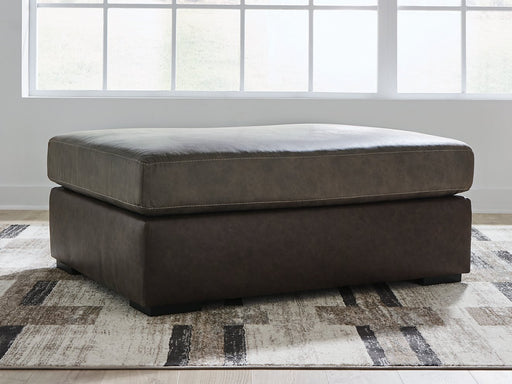 Ashley Furniture Castille Way oversized accent ottoman with plush fabric and wooden legs, positioned in a modern living room setting.