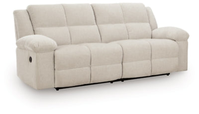 Ashley Furniture Orlen reclining sofa in a neutral fabric, shown from an angled view highlighting the plush cushions and recliner mechanism.