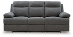 Ashley Furniture side-swipe reclining sofa with drop-down table, shown in a head-on view with closed side panels and sleek design.