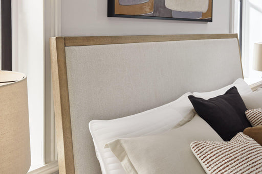 Ashley Furniture Tomtyn upholstered bed with a padded headboard and neutral fabric, showcasing a modern bedroom style.