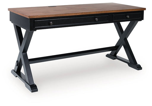 Ashley Furniture Wildenauer 60-inch home office desk shown from an angled closed view, featuring a sleek wooden surface and modern design.