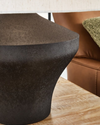 Dolanham table lamp by Ashley Furniture with a sleek design, featuring a fabric shade and wooden base on a modern side table.