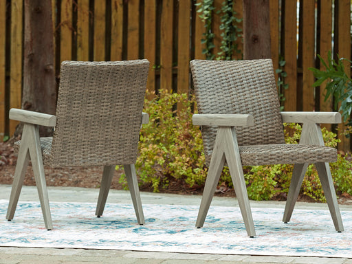 Set of two Ashley Furniture outdoor dining chairs with armrests, woven rattan-style seats and metal frames, suitable for patio dining.