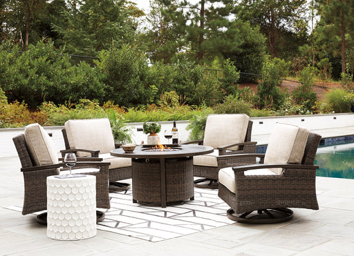 Outdoor seating set featuring a Paradise Trail fire pit table with four Nuvella swivel lounge chairs by Ashley Furniture.